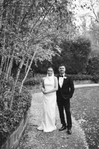 Elegant bride and groom standing outdoors in wedding attire.