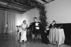 Elegant couple at a formal event with children and guests in a stylish venue.